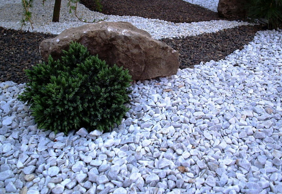 Piedra triturada triturada de diferentes colores en un parterre de jardín