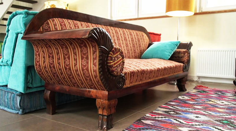 Krøllete armlener på sofaen er dekorert med utsmykkede utskjæringer