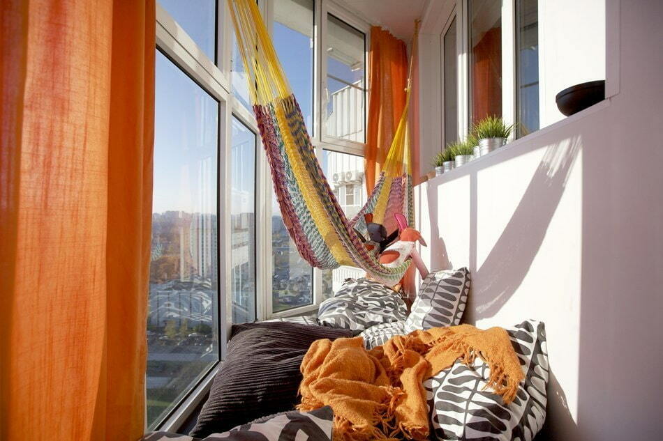 Sitzecke auf dem Balkon mit orangefarbenen Vorhängen