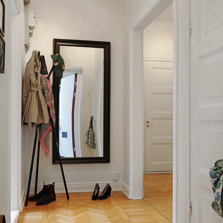 Specchio da parete con cornice nera in un corridoio bianco