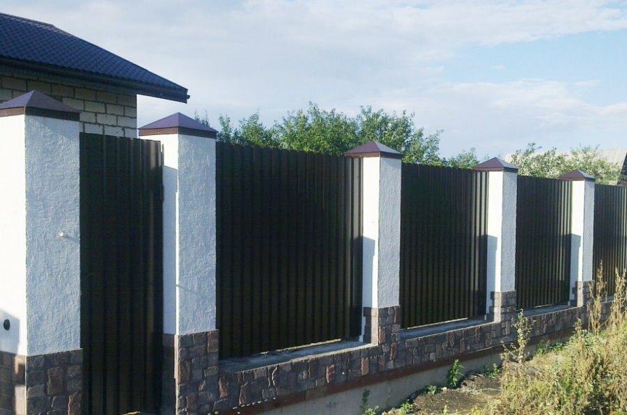 Decoración de piedra de los postes de soporte de una cerca con tramos de una hoja perfilada