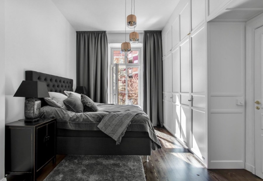 Silberne Vorhänge in einem kleinen Schlafzimmer mit Einbaumöbeln