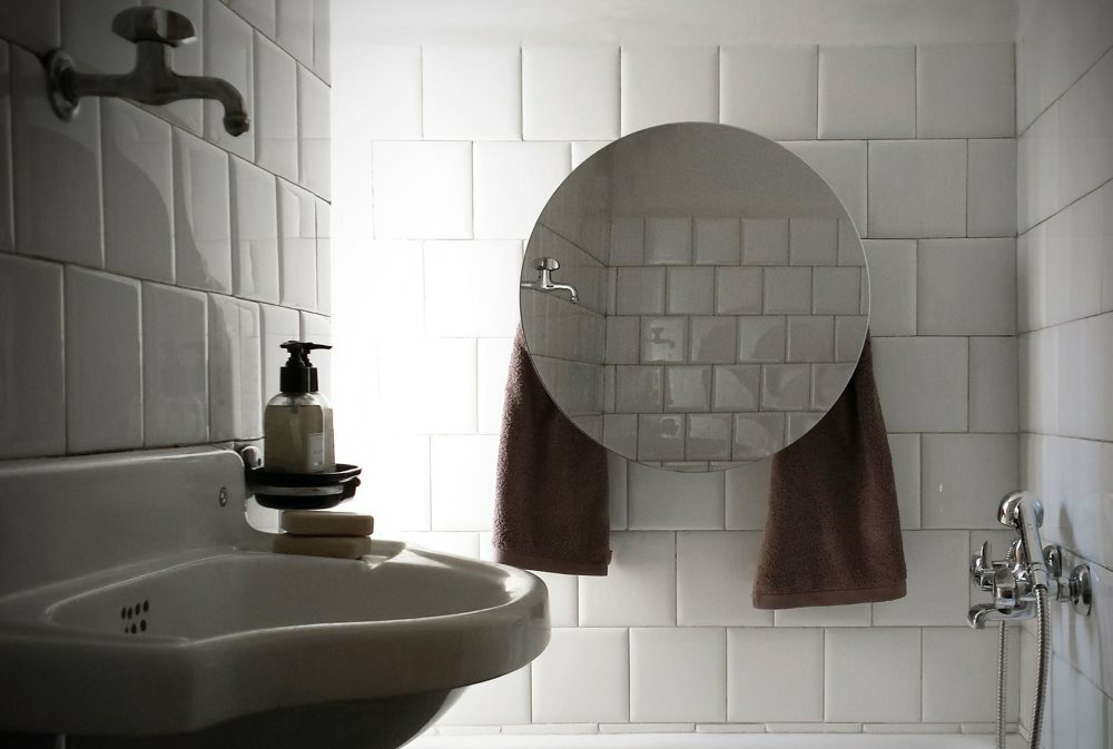 Vyhřívaný věšák na ručníky se zrcadlem na stěně koupelny