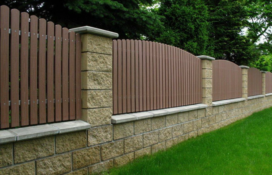 La clôture en bois s'étend sur des piliers avec garniture en pierre