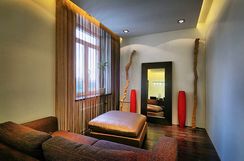 Interiér obývačky je vyrobený v monochromatických tónoch a zdobený jasnými akcentmi vo forme šarlátových váz.